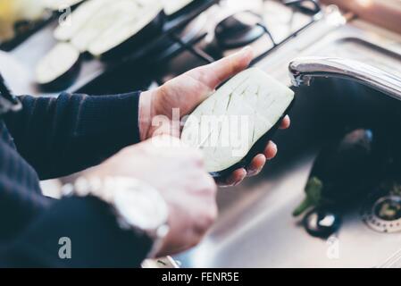 Mans hands making cuts on aubergine halves in kitchen Stock Photo