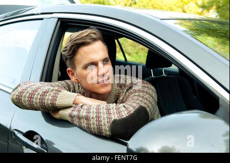 Young man leaning and looking out from car window Stock Photo