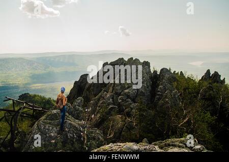 Rear view of teenage boy hiking on rugged rock formation, Russia Stock Photo
