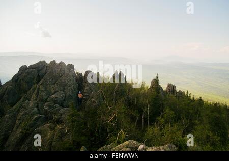 Rear view of teenage male hiker climbing rugged rock formation, Russia Stock Photo