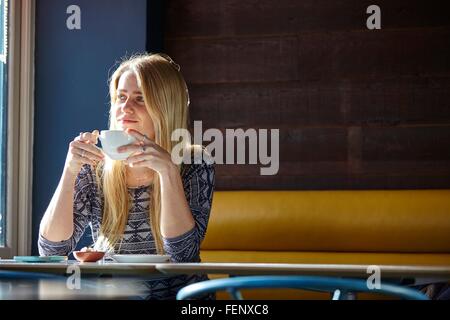 Young woman alone in cafe drinking coffee Stock Photo