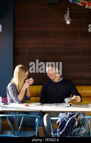 Young couple on date in cafe drinking coffee and reading magazine Stock Photo