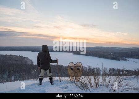 Rear view of male hiker looking out over snow covered landscape, Ural, Russia Stock Photo
