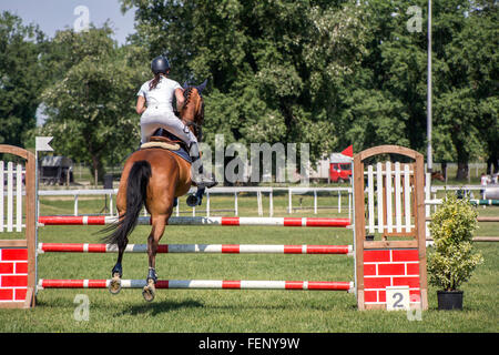 Young girl jumping on horseback competing in equestrian tournament Stock Photo