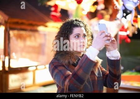 Young woman at amusement park using smartphone to take selfie Stock Photo