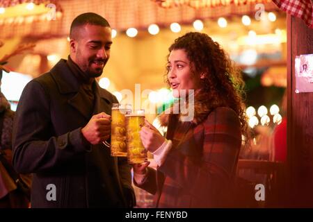 Couple on night out holding glass on beer making a toast Stock Photo