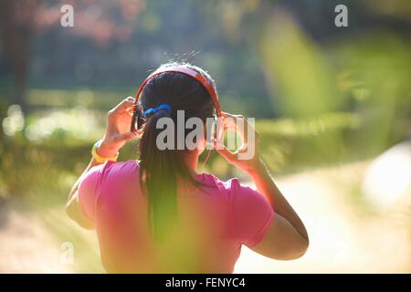 Rear view of mature woman with pony tail wearing headphones Stock Photo