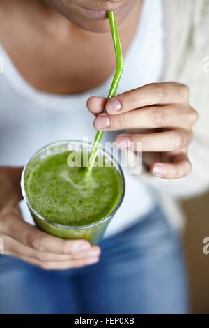 Woman drinking green smoothie with straw Stock Photo