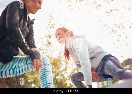 Low angle view of female runners stretching legs in park Stock Photo