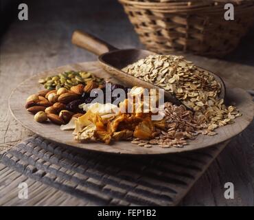 Dried fruits, nuts and oats on wooden plate Stock Photo