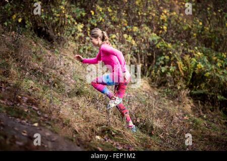 Side view of young woman wearing sport wear running up hill Stock Photo