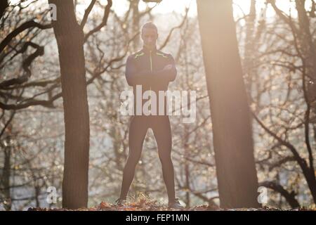 Full length front view of mid adult man standing in forest arms folded looking at camera smiling Stock Photo