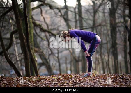 Side view of young woman wearing sports clothing bending over hands on knees, exhausted Stock Photo