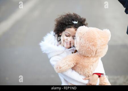 High angle view of girl, eyes closed hugging soft toy Stock Photo