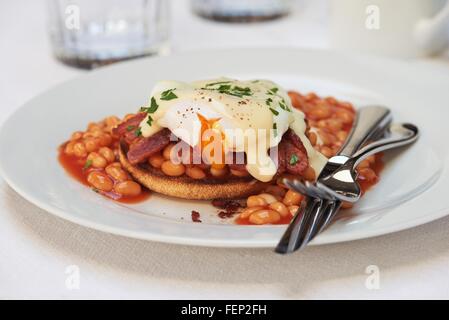 Poached egg, bacon and beans with hollandaise sauce on english muffin Stock Photo