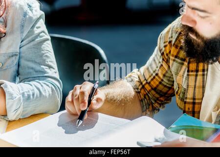 Cropped shot of male and female college students reading at desk Stock Photo