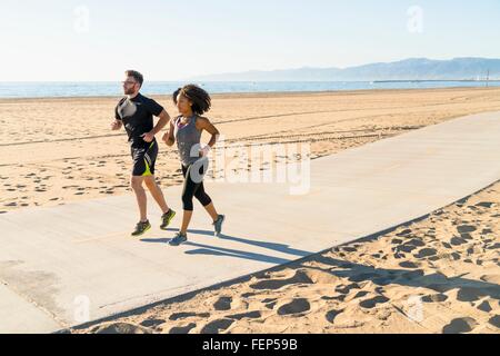 Couple running on pathway at beach Stock Photo
