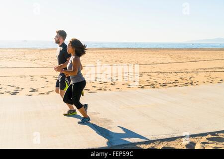 Couple running on pathway at beach Stock Photo