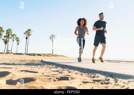 Couple running on pathway at beach, low angle view Stock Photo