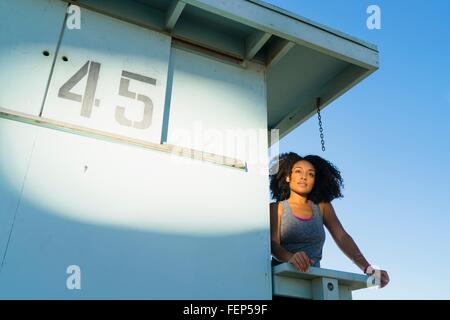 Mid adult woman standing on look out tower at beach, looking at view Stock Photo