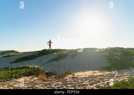 Young man running along sand dunes Stock Photo