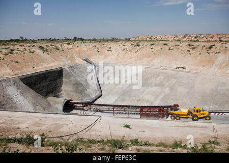 A mining vehicle is parked just outside on the entrance of an inclined diamond mine shaft in the desert Stock Photo