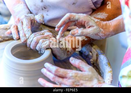 Close up of female potter and mature student hands making pot on potters wheel Stock Photo
