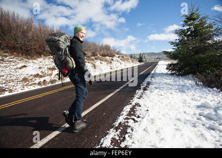 Young male hiker hiking on rural road in snow covered landscape, Ashland, Oregon, USA Stock Photo