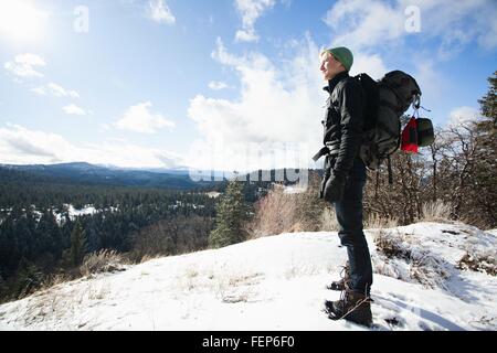 Young male hiker looking out from snow covered landscape, Ashland, Oregon, USA Stock Photo