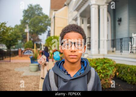 Sad boy standing beside school Stock Photo