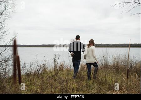 Young family walking outdoors, beside lake, rear view Stock Photo