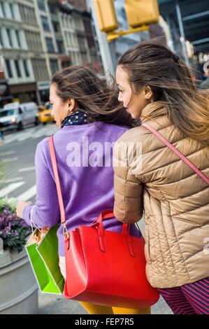 Rear view of young female adult twins looking sideway to cross city road Stock Photo