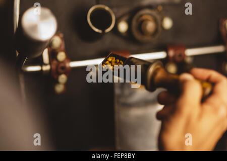 Man putting coffee beans into coffee roaster, close-up Stock Photo