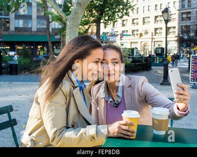 Young adult female twins taking selfie in city park Stock Photo