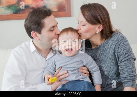 Parents kissing son on head at home Stock Photo