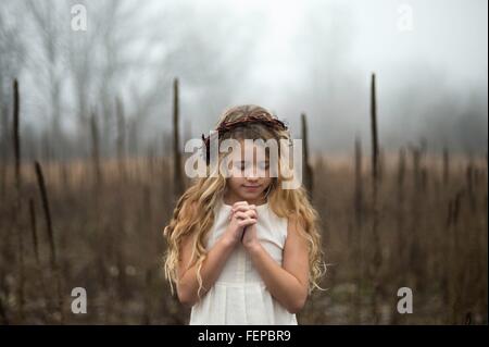 Portrait of long blond haired girl with head bowed in misty marsh Stock Photo