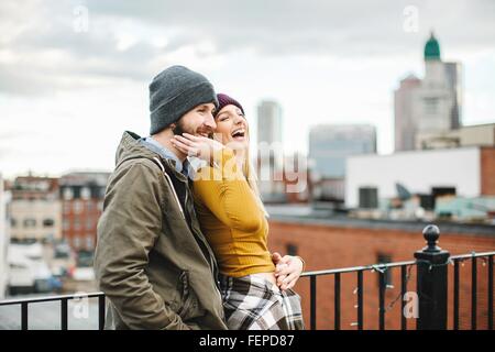 Young couple laughing on city rooftop terrace Stock Photo