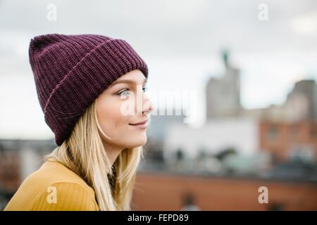 Portrait of young woman wearing knitted hat gazing from rooftop Stock Photo