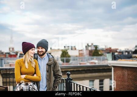 Young couple standing on city rooftop terrace Stock Photo