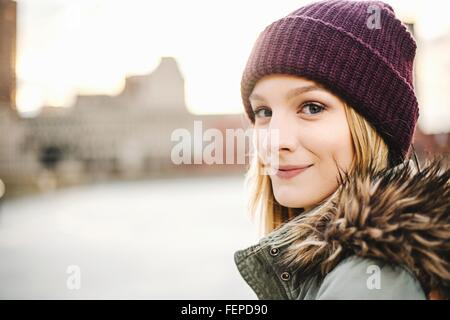 Portrait of young woman wearing knitted hat and fur hood Stock Photo