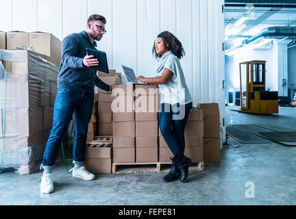 Full length view of colleagues in warehouse looking at digital tablet Stock Photo