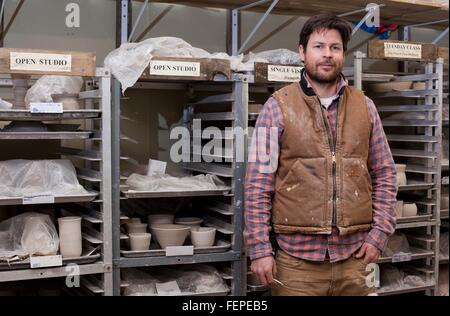 Potter in storage room, hand in pocket looking at camera smiling Stock Photo