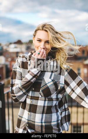 Portrait of young woman with flyaway hair on rooftop terrace Stock Photo
