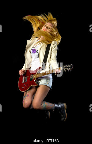 Young blonde girl jumping with electric guitar Stock Photo