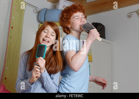 Children, boy and girl singing into hairbrush as microphone, Germany Stock Photo