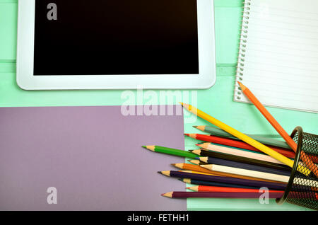 Tablet with notepad and colorful pencil on green wooden table Stock Photo