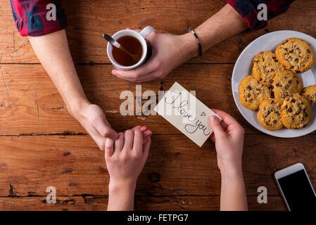 Unrecognizable mans and womans hands. Romantic message. Tea and cookies. Stock Photo