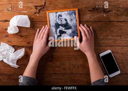 Unrecognizable sad woman holding broken picture of couple in love. Stock Photo