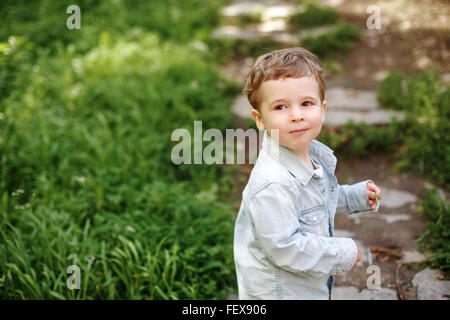 Two Years Old Little Boy Walking in the Summer Park Outdoors. Cute Blonde Kid in Jeans Clothing. Stock Photo