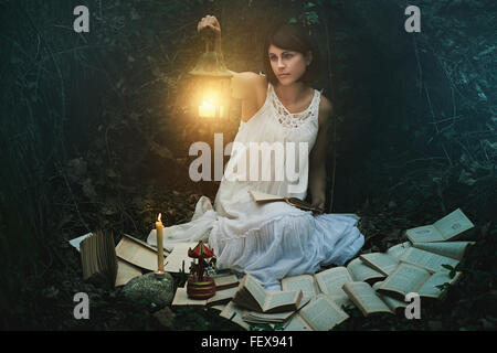 Beautiful woman with lantern in a dark forest. Surreal and fantasy Stock Photo